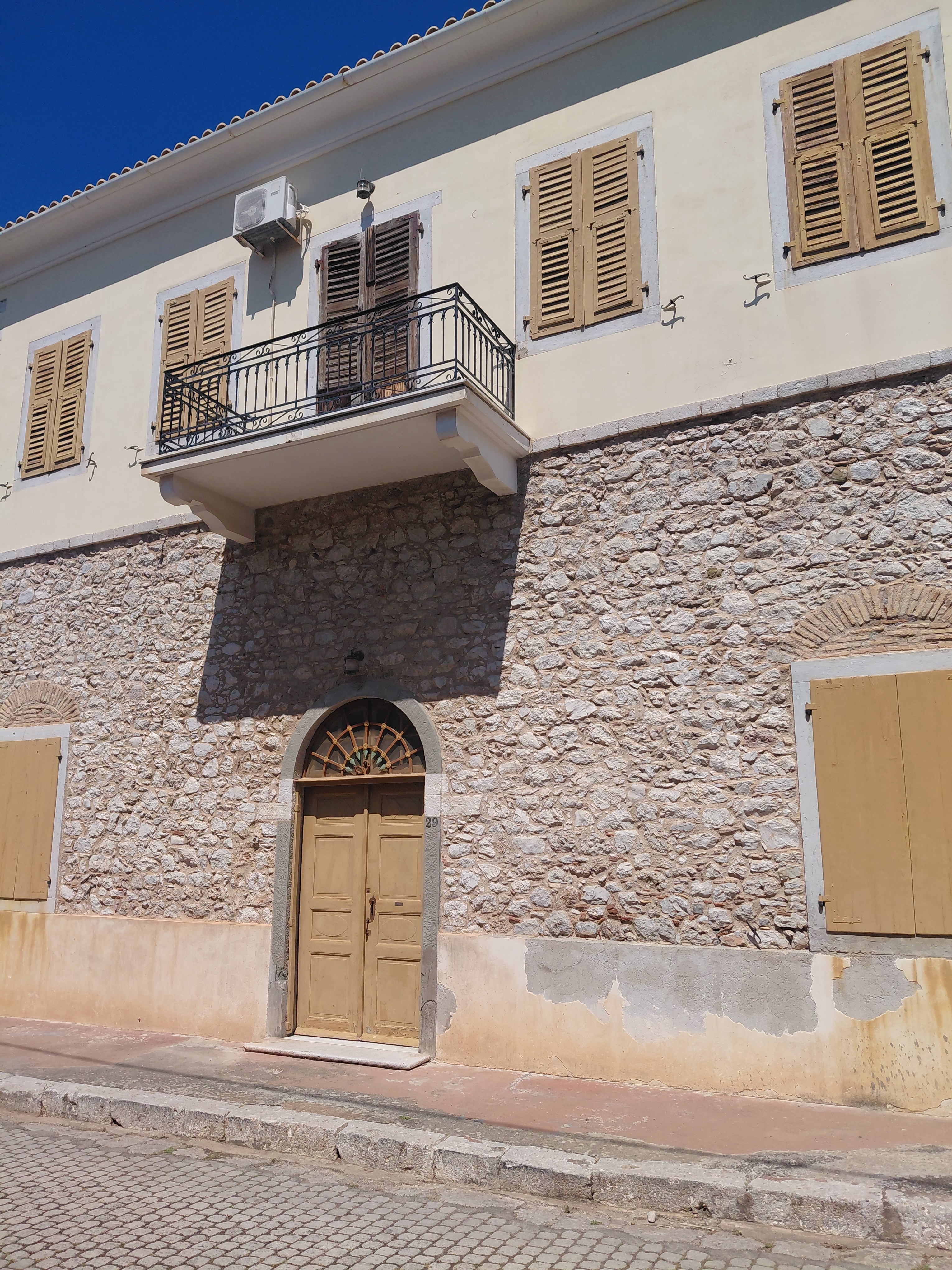 Street facade with arched stone doorway and iron balcony