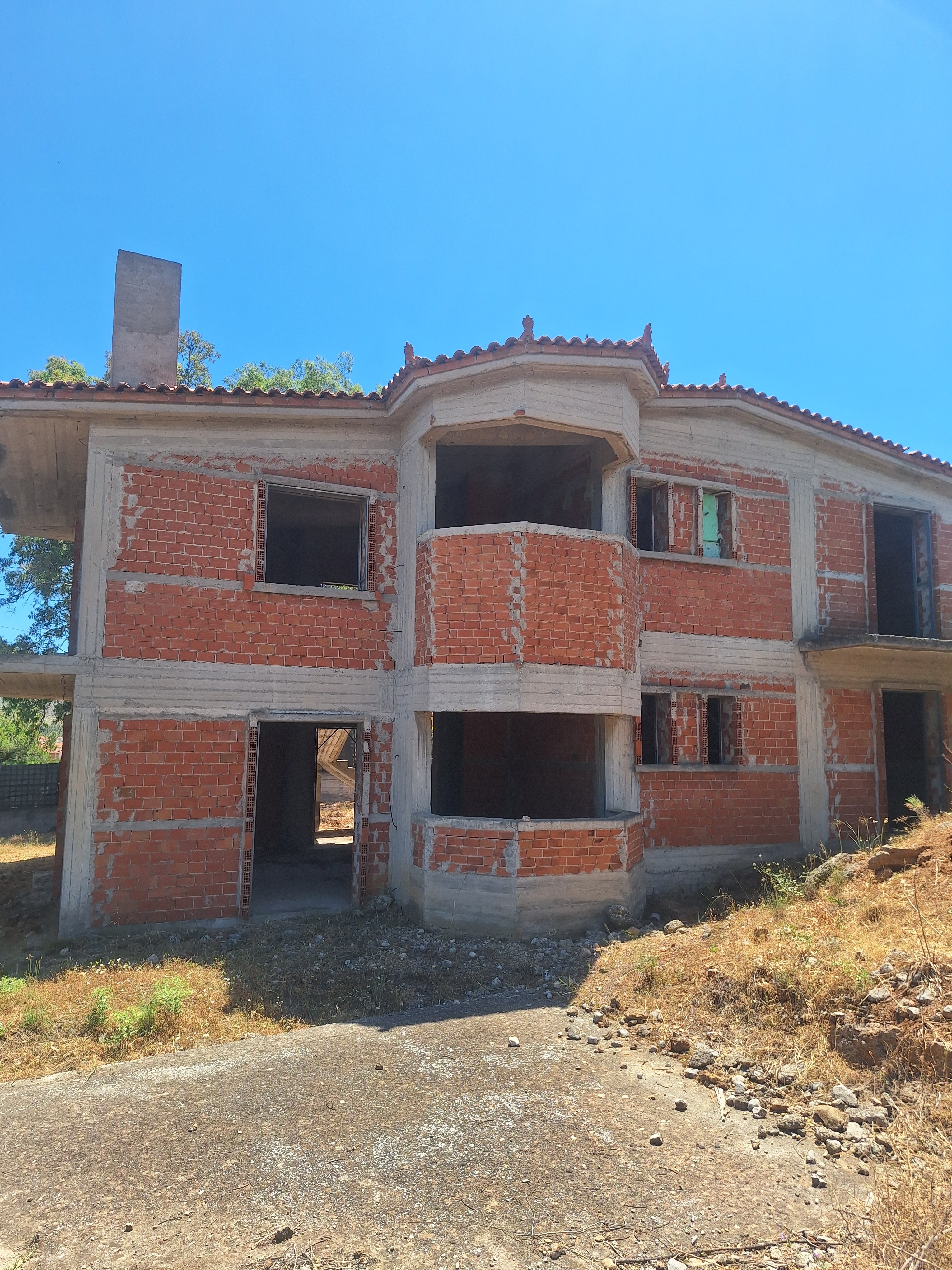 The two-storey shell today — brick and concrete, roofed